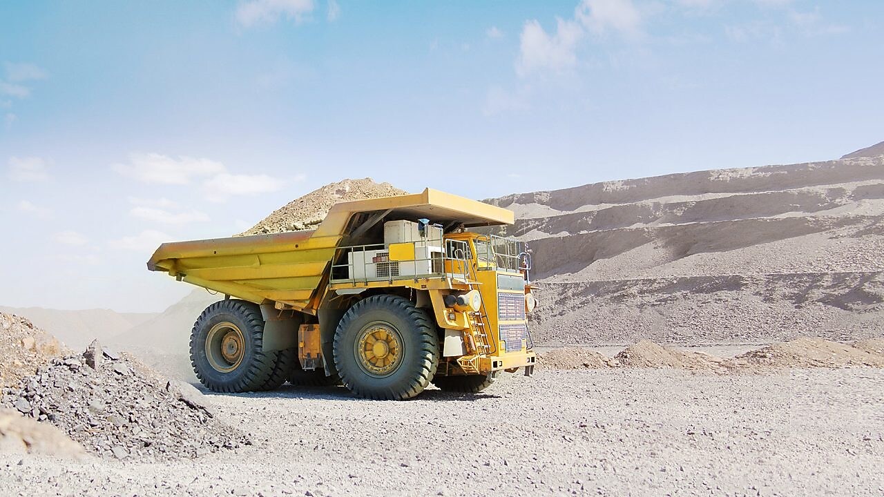 yellow dumper truck driving through gravel