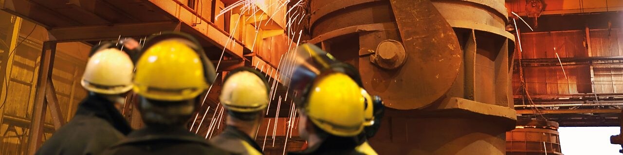 workers watching heavy machinery in a metal processing plant