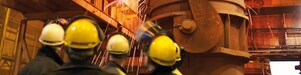 workers watching heavy machinery in a metal processing plant