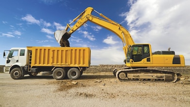 yellow excavator loading mud into a truck
