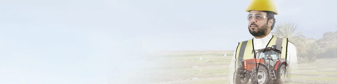 man reading a document with a background of fields and a red tractor