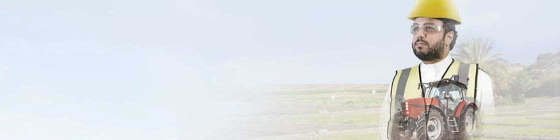 man reading a document with a background of fields and a red tractor