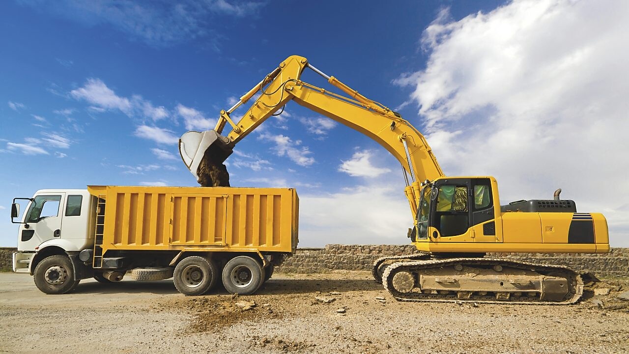 yellow excavator loading mud into a truck